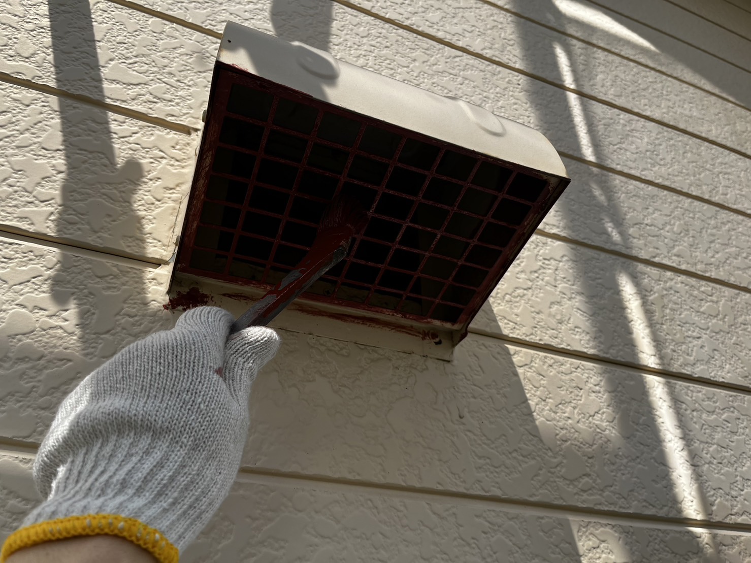 新潟市の付帯部塗装で換気フードを塗装している様子